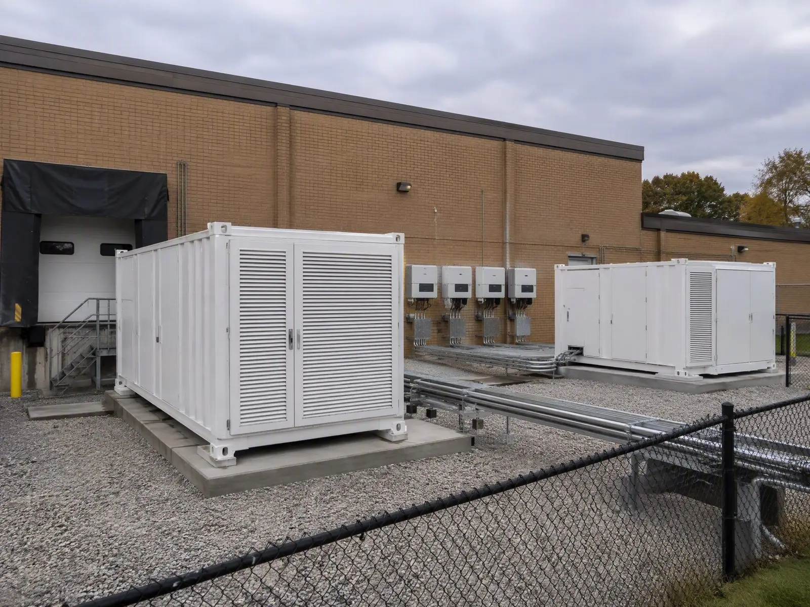 Containerized commercial battery storage cabinets and hybrid inverters installed behind a US warehouse